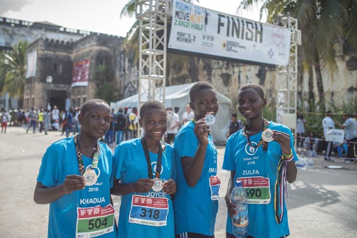 Four young women from Tanzania how off their medals at the end of the Zanzibar Half Marathon, January 2018
