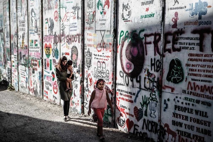 A mother and her children walking along the illegal Israeli Separation Wall that cuts through Bethlehem surrounding it on three sides.