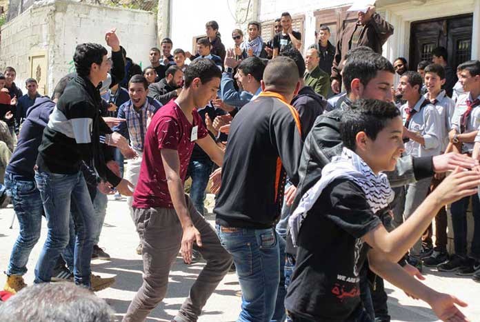 A group of young Palestinian men dancing in the street.