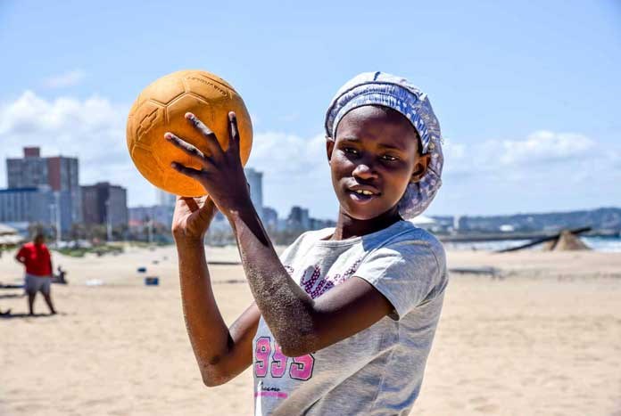 A young women playing beach volleyball on the beach in Durban, South Africa.
