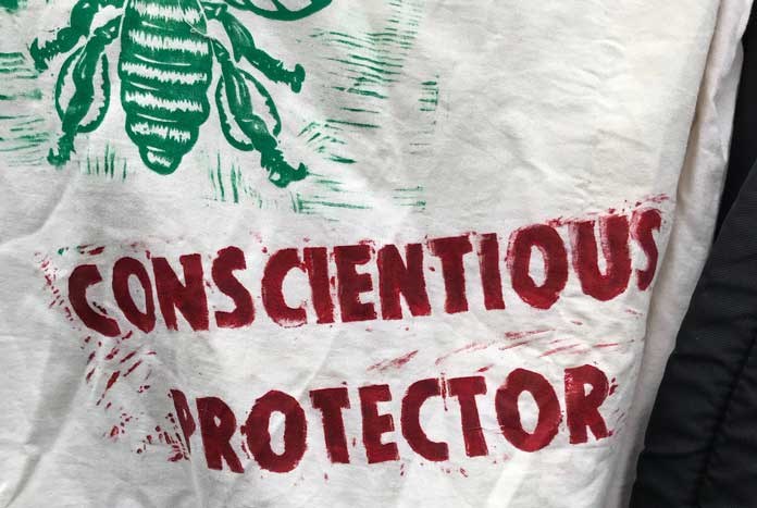 An Extinction Rebellion banner reads 'Conscientious Protector'.