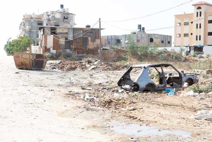 A bombed-out car in rubble – Gaza City.