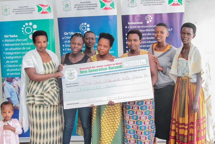 Young women in Burundi holding a large charity cheque.