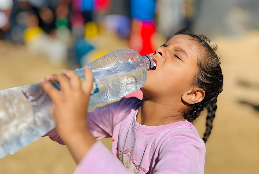 A young girl drinking clean water from a plastic bottle in Gaza.
