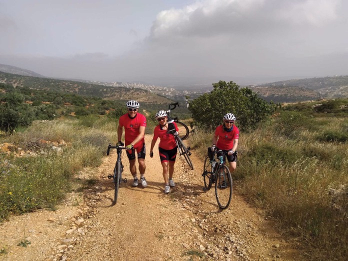 Three Amos Road Club members walking with their bikes.