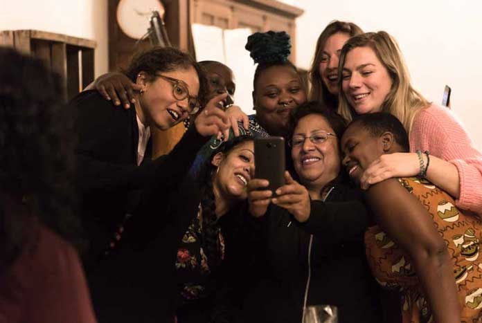 A group of women laughing while taking a Selfie.