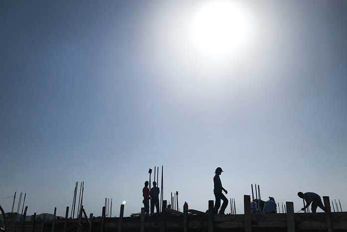 Builders on the roof of a Palestinian home at sunset.