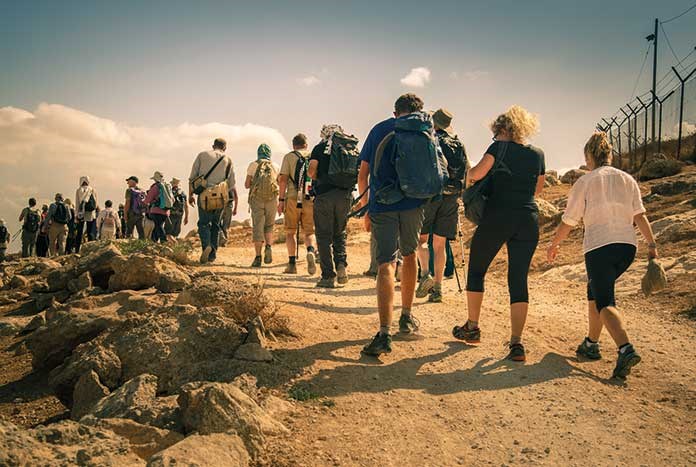 A large group of people walking across the Palestinian wilderness.
