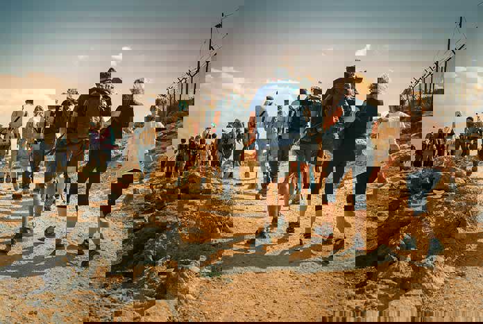A large group of people walking across the Palestinian wilderness.