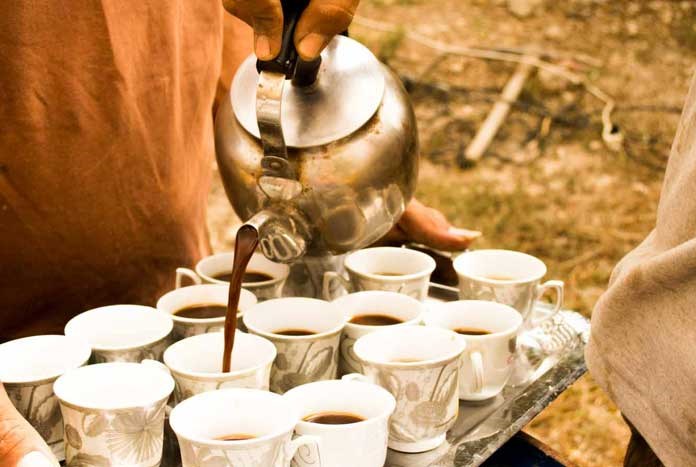 Coffee being poured and shared on a hillside.