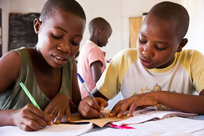 Two young people writing in their school books.
