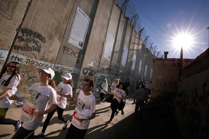 Participants of the Palestine Marathon running passed the Separation Wall in Bethlehem.