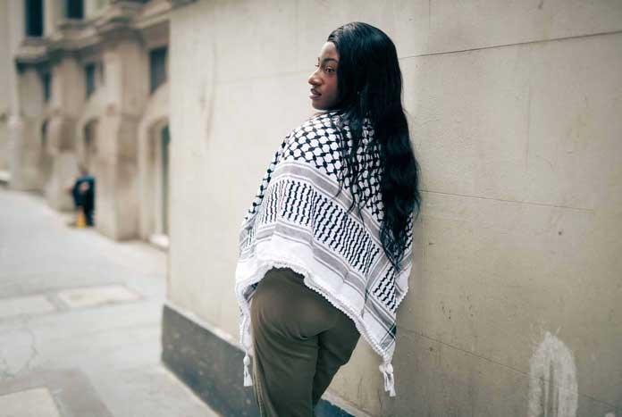 A young woman wearing a traditional Palestinian Keffiyeh scarf.