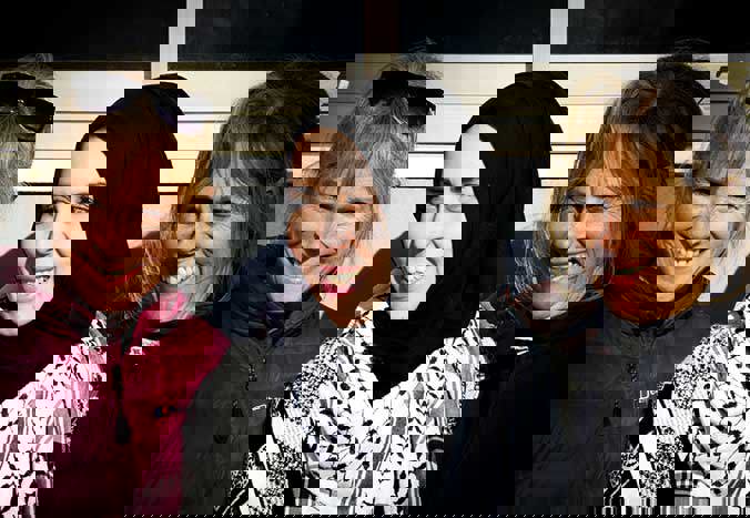 Three women smiling together.