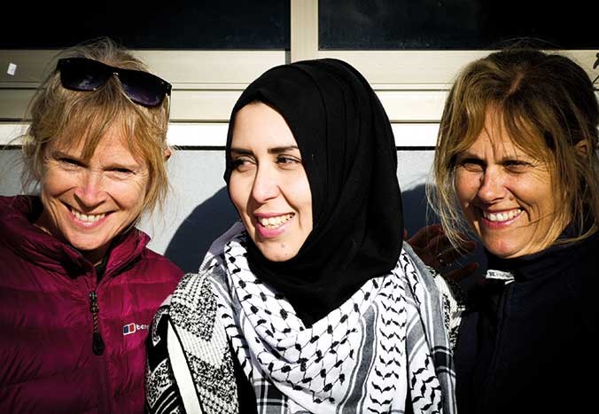Three women smiling together.