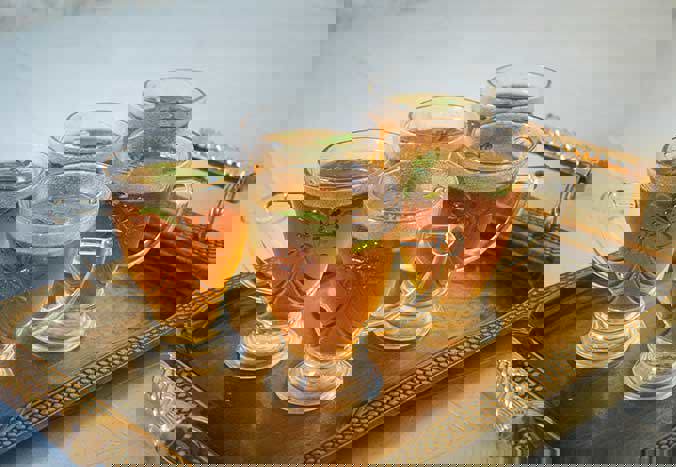 A tray of five ornate glass cups containing mint tea.