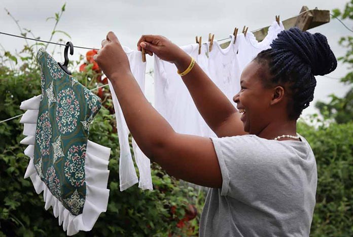 A young South African women smiles while hanging out her washing.