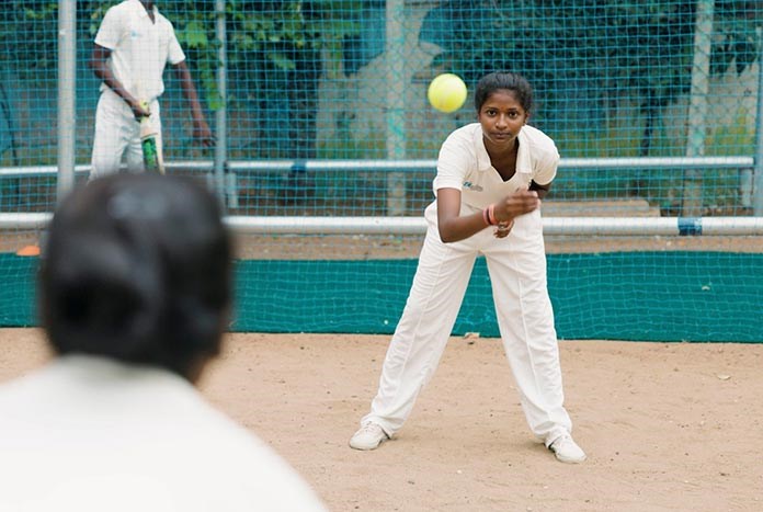A young Indian women practising her cricket skills.