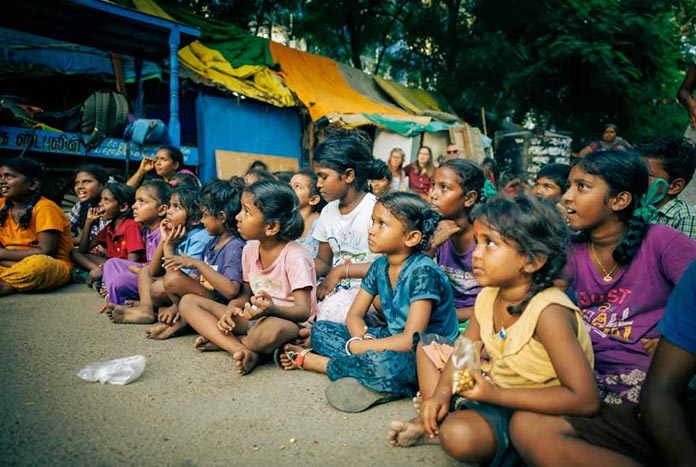 Young girls sitting on the pavement in India.