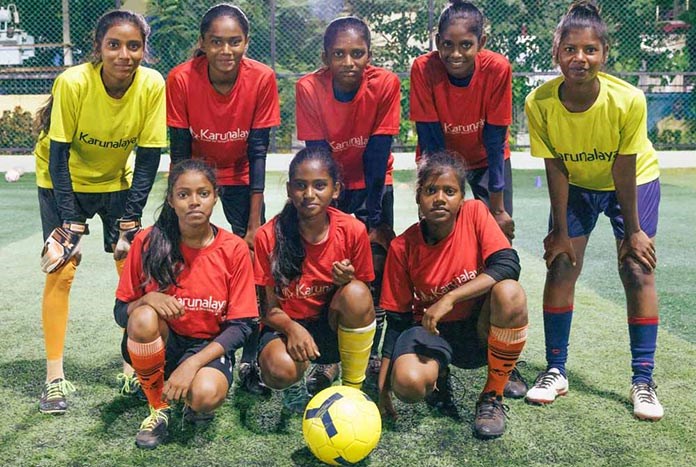 Young Indian women line up in their football kit after practice.