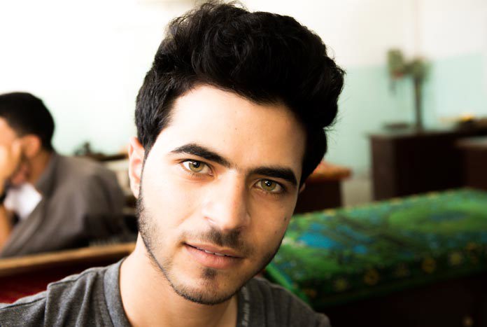 A young Gazan man in a workshop smiling for the camera.