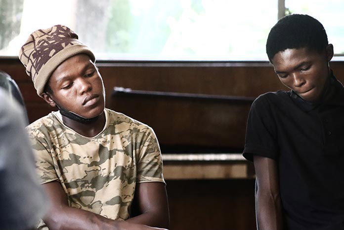 Two young South African men looking at the floor.