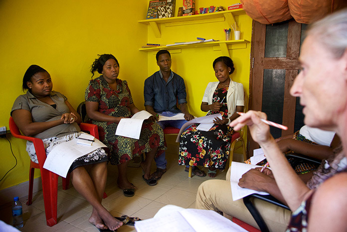 A group of women in Tanzania sitting on chairs talking together.