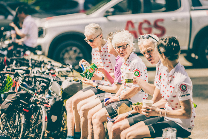 Amos Road Club members sitting on a wall eating lunch.