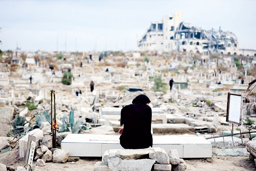 A woman sits by the grave of a family member in Gaza.