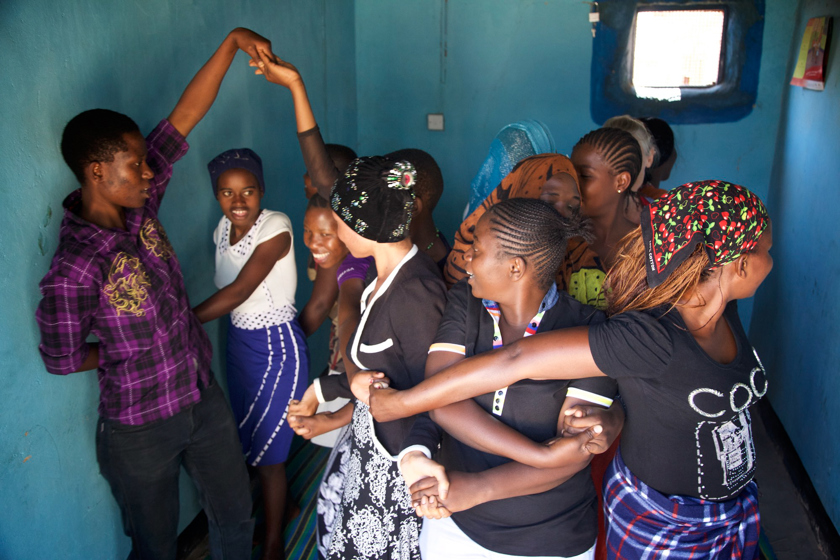 Young women from Cheka Sane Tanzania working and smiling together in a group session.