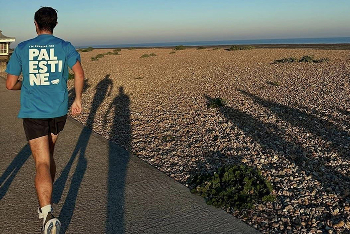 A marathon runner runs along a beach.