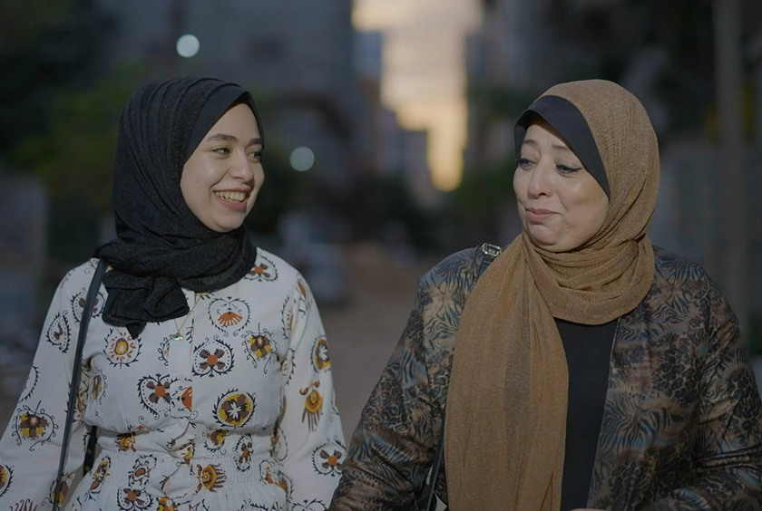 A Palestinian mother and daughter walking and smiling in Gaza.