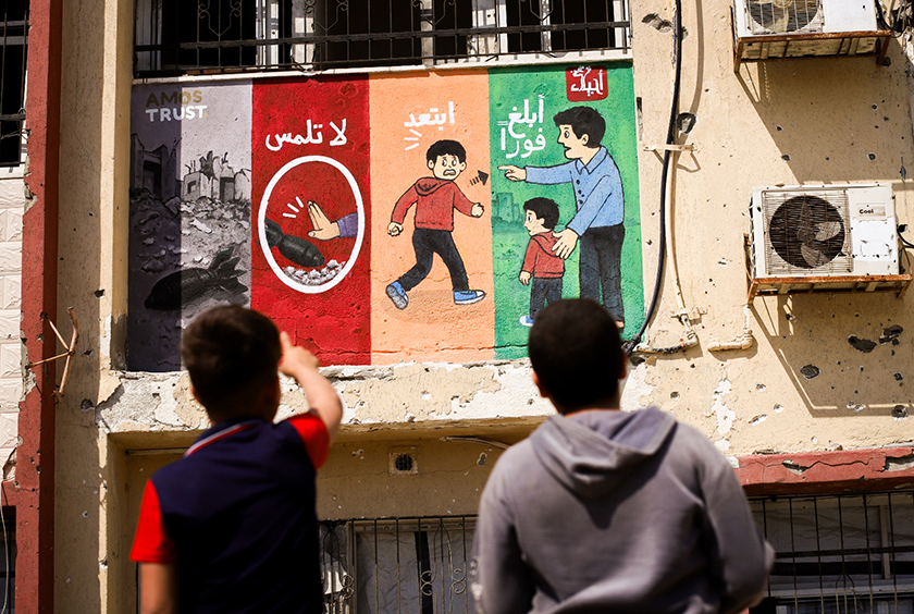 Two young children looking at a mural in Gaza.