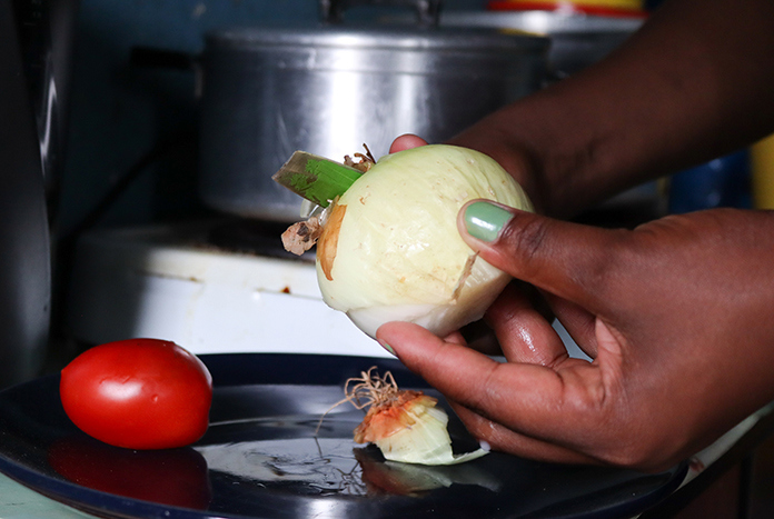 A South African woman peels an onion.